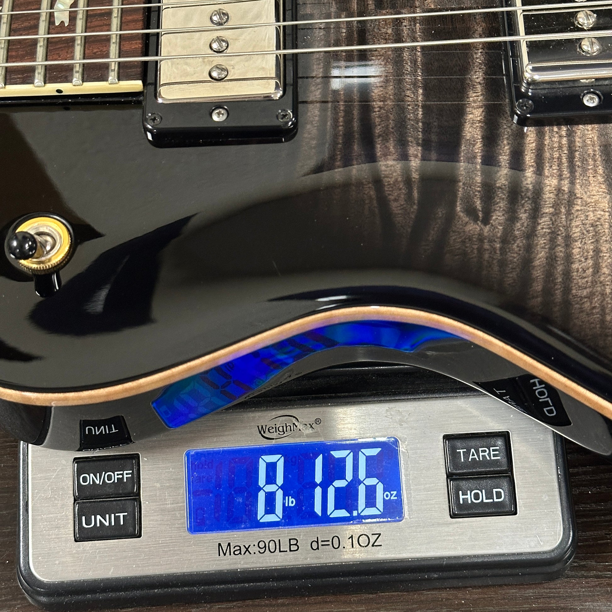 Black electric guitar on a digital scale displaying weight