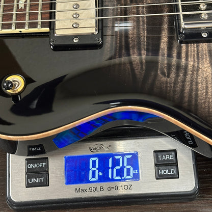 Black electric guitar on a digital scale displaying weight