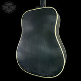 Back view of a black acoustic guitar with a visible brand logo in the corner.