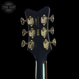 Close-up of a guitar headstock with tuning pegs on a black background, featuring the Tone Shop logo.
