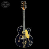 Electric guitar with a black and gold design on a black background, featuring the Tone Shop logo.