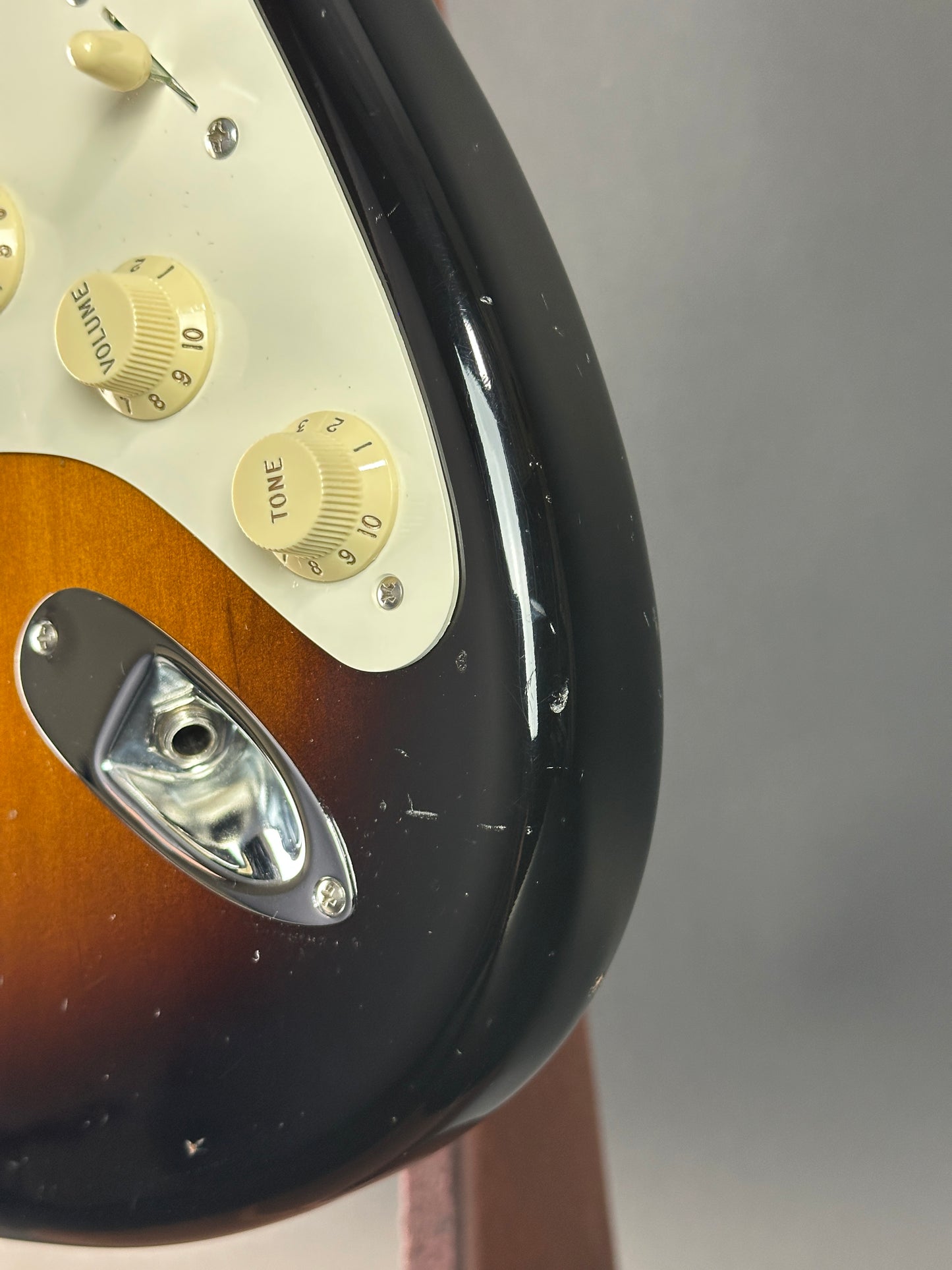 Close-up of a guitar's control panel with knobs and brand logo.
