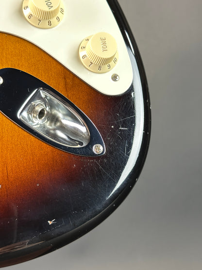 Close-up of a guitar's control knobs and pickguard on a gray background