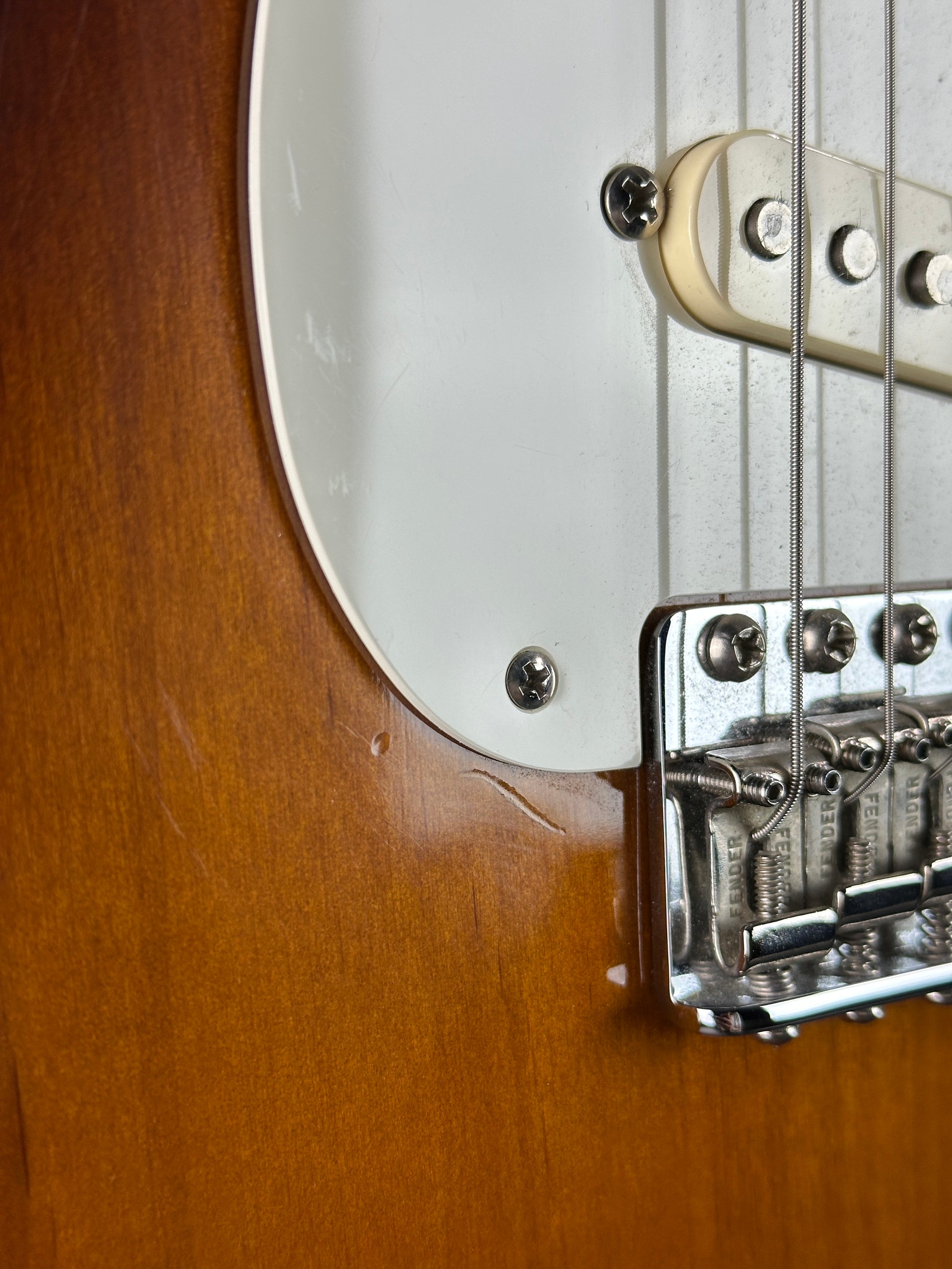 Close-up of a guitar's bridge and strings on a wooden surface