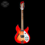 Red electric guitar with a white pickguard on a black background, featuring 'Tone Shop' branding.