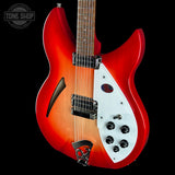 Red electric guitar with a white pickguard on a black background, featuring the Tone Shop logo.