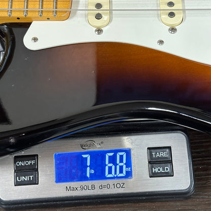 Digital scale displaying weight of a guitar on a wooden surface
