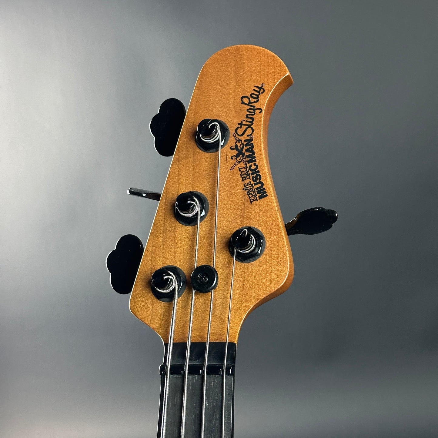Close-up of a guitar headstock with brand name on a gray background