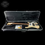 Electric bass guitar in a clear case with 'Tone Shop' branding.