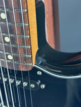 Close-up of a guitar's neck and headstock with a blurred background