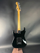 Black electric guitar on a gray background