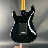 Black electric guitar with a white pickguard on a gray background