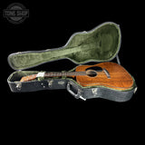 Acoustic guitar in an open case with 'Tone Shop' branding.