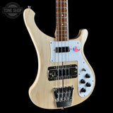 Electric bass guitar with a light wood finish on a black background, featuring the Tone Shop logo.