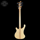 Bass guitar with a clear finish on a black background, featuring the Tone Shop logo.
