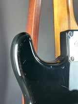 Close-up of a guitar neck with a black pickguard on a gray background