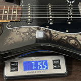 Black electric guitar on a digital scale displaying weight