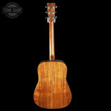 Back view of a wooden acoustic guitar with 'Tone Shop' logo.