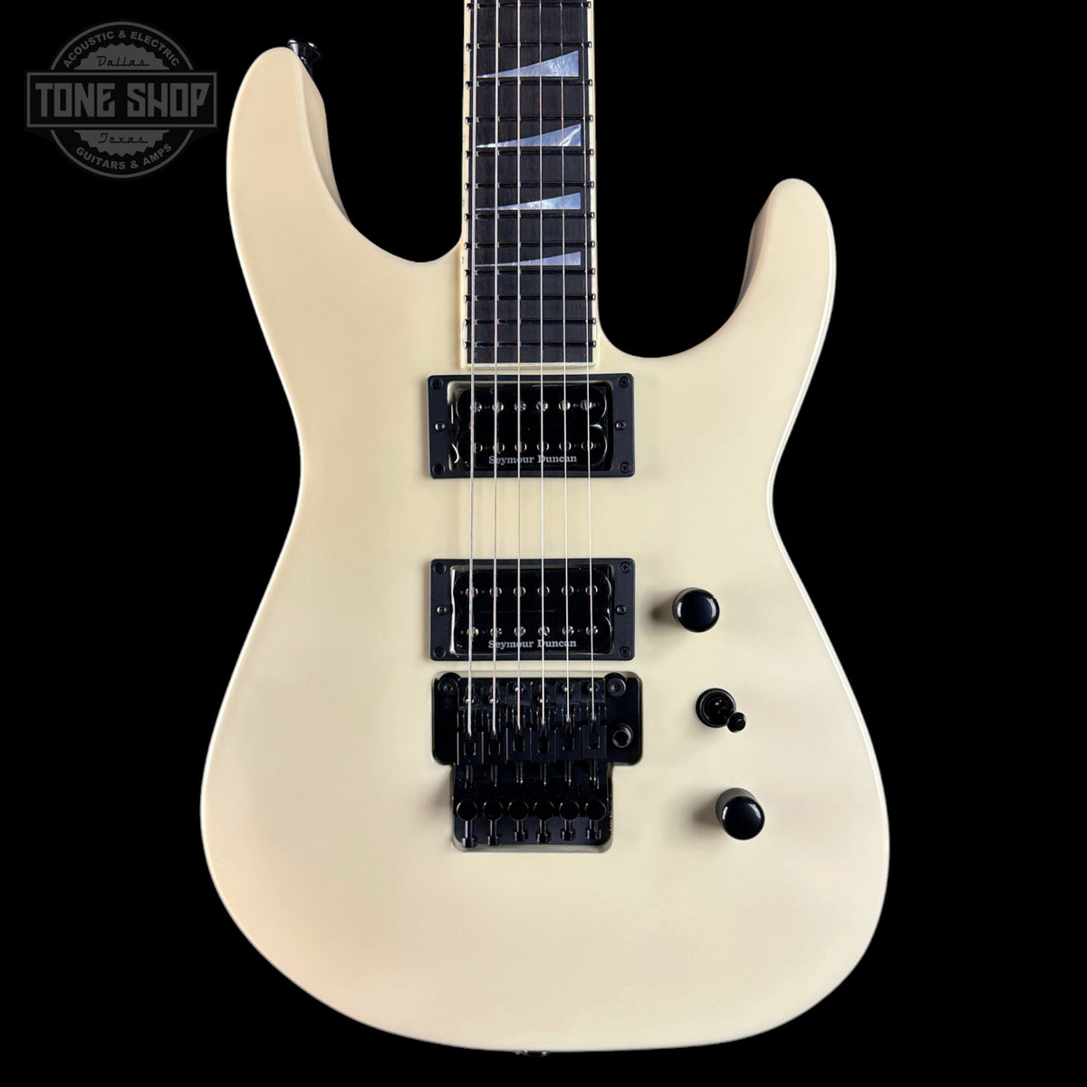 White electric guitar with black pickups on a black background, featuring 'Tone Shop' logo.