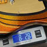 Gold and orange guitar on a digital scale displaying weight.
