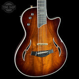 Brown acoustic guitar with a visible brand logo on a black background