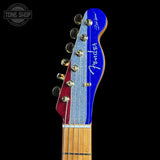 Close-up of a guitar headstock with a blue and red design on a black background, featuring the 'Tone Shop' logo.