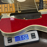 Red electric guitar on a digital scale displaying weight