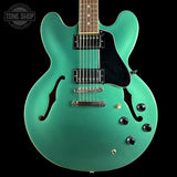 Turquoise electric guitar with a black pickguard on a black background, featuring 'Tone Shop' branding.