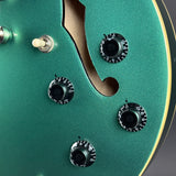 Close-up of a green electric guitar's control panel with knobs and switches.