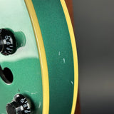 Close-up of a green electric guitar with control knobs on a blurred background
