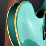 Close-up of a green electric guitar with a dark background
