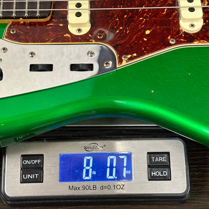 Green electric guitar next to a digital scale displaying weight