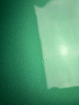 Close-up of green textured fabric with a light source creating a shadow.