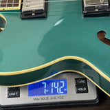 Green electric guitar on a digital scale displaying weight