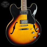 Electric guitar with a sunburst finish on a black background, featuring the Tone Shop logo.
