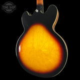 Close-up of a guitar's back with a sunburst finish on a black background, featuring the Tone Shop logo.