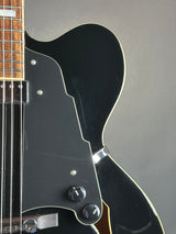 Close-up of a black electric guitar with a gray background