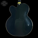 Back view of a black electric guitar with 'Tone Shop' logo in the corner.