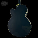 Glossy black electric guitar on a black background with 'Tone Shop' logo.