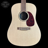 Acoustic guitar with a natural finish on a black background, featuring the Tone Shop logo.