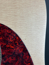Close-up of a guitar with a red and brown tortoiseshell pattern on a beige background