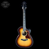 Acoustic guitar with a sunburst finish on a black background, featuring the Taylor logo.