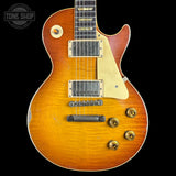A classic electric guitar with a sunburst finish, featuring a cream pickguard, gold-toned hardware, and a black fretboard, shown against a solid black background with a Tone Shop watermark in the top left corner.