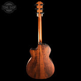 Back view of a wooden guitar with 'Tone Shop' branding.