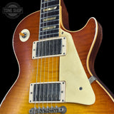 Close-up of a double-cutaway electric guitar body with a sunburst finish, cream pickguard, black humbucker pickups, and a black neck, shown against a black background with a Tone Shop watermark.
