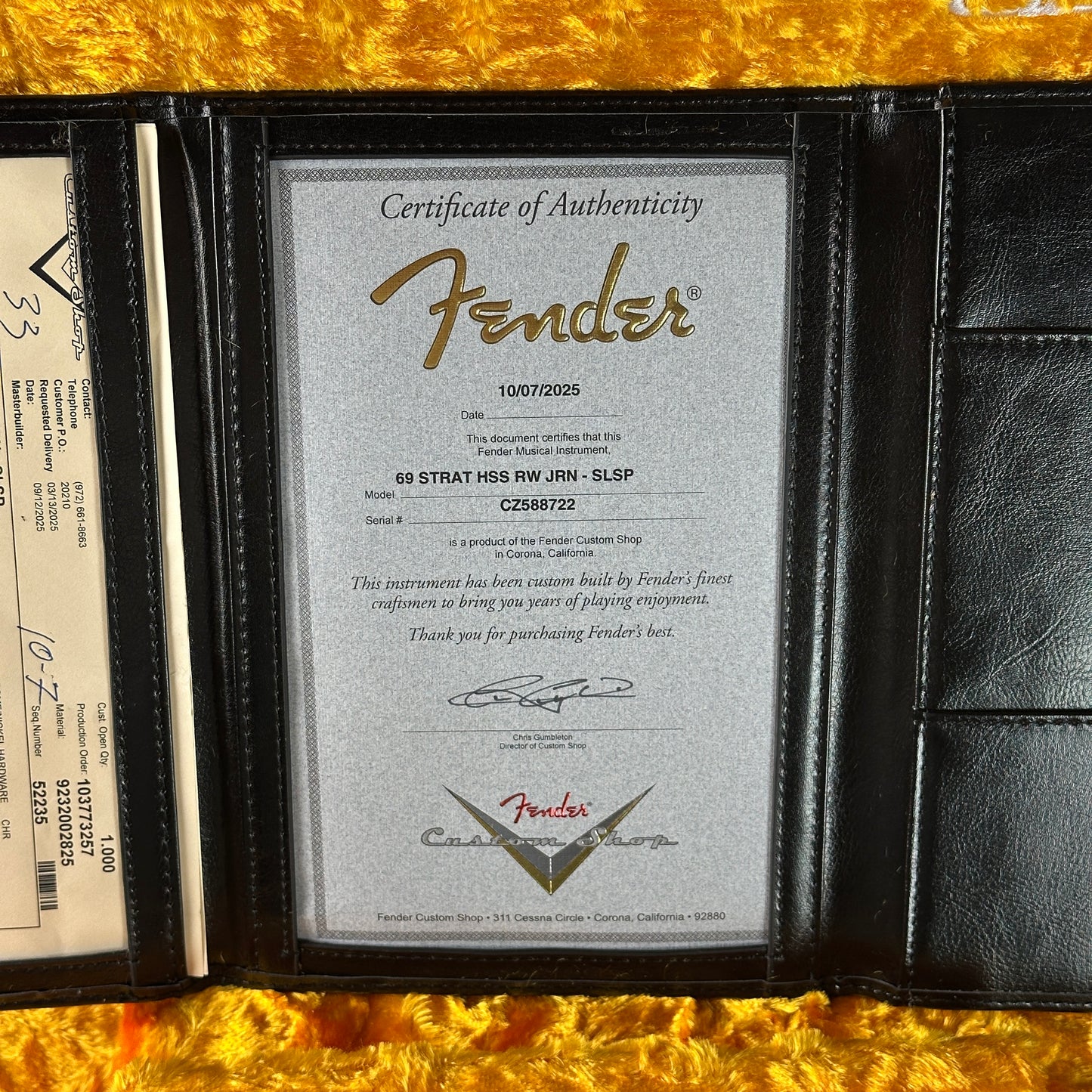 Fender certificate of authenticity in a black leather wallet on a gold surface