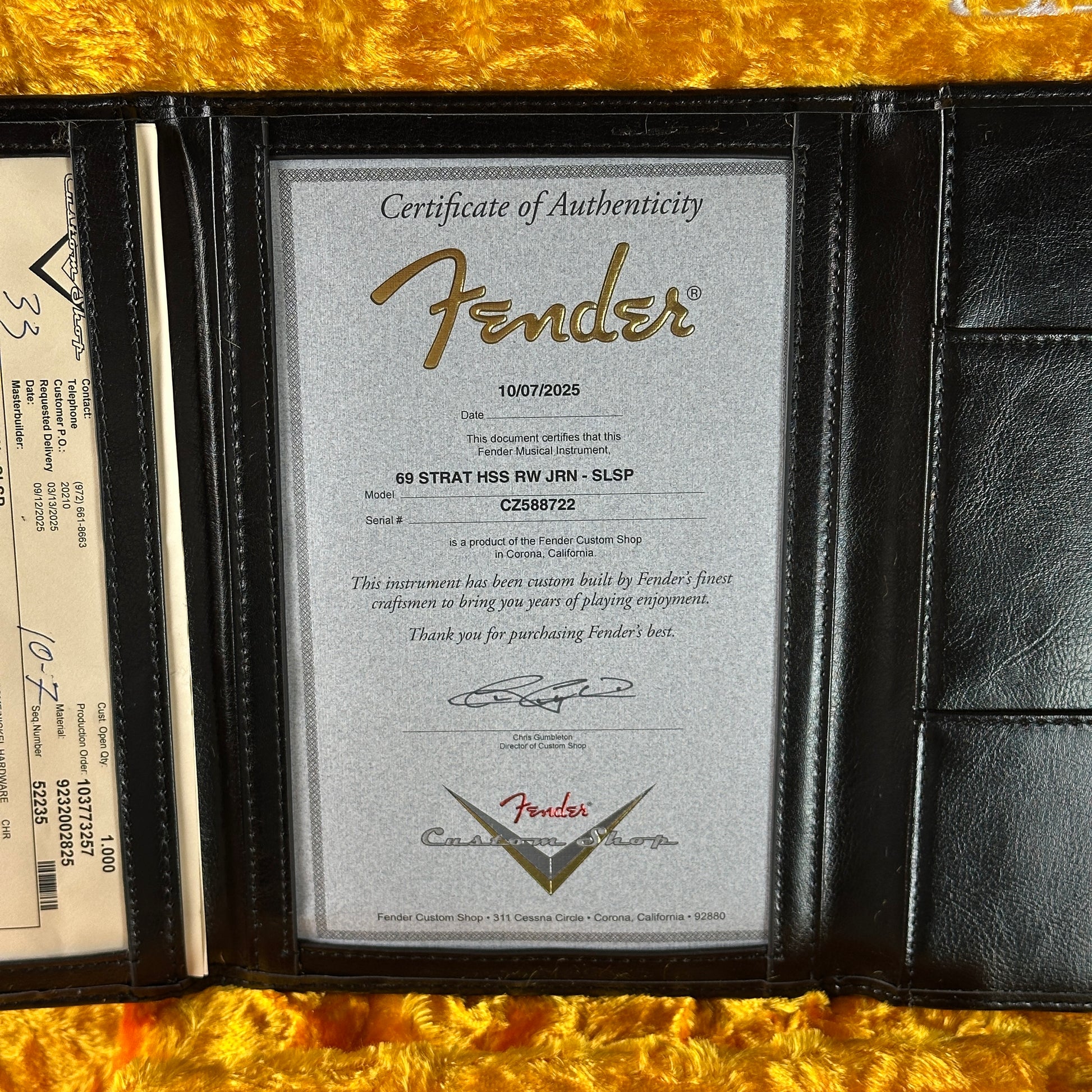 Fender certificate of authenticity in a black leather wallet on a gold surface