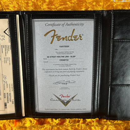 Fender certificate of authenticity in a black leather wallet on a gold surface