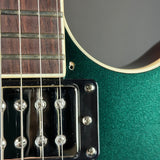 Close-up of a green electric guitar with focus on the neck and body.