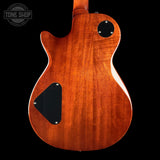 Wooden electric guitar body with a black pickguard on a black background, featuring 'Tone Shop' logo.
